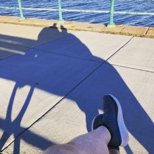 legs in shorts with water and sun in the distance