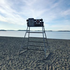 lifeguard chair on beach with bright blue sky and white clouds, Boston Harbor Islands in the distance